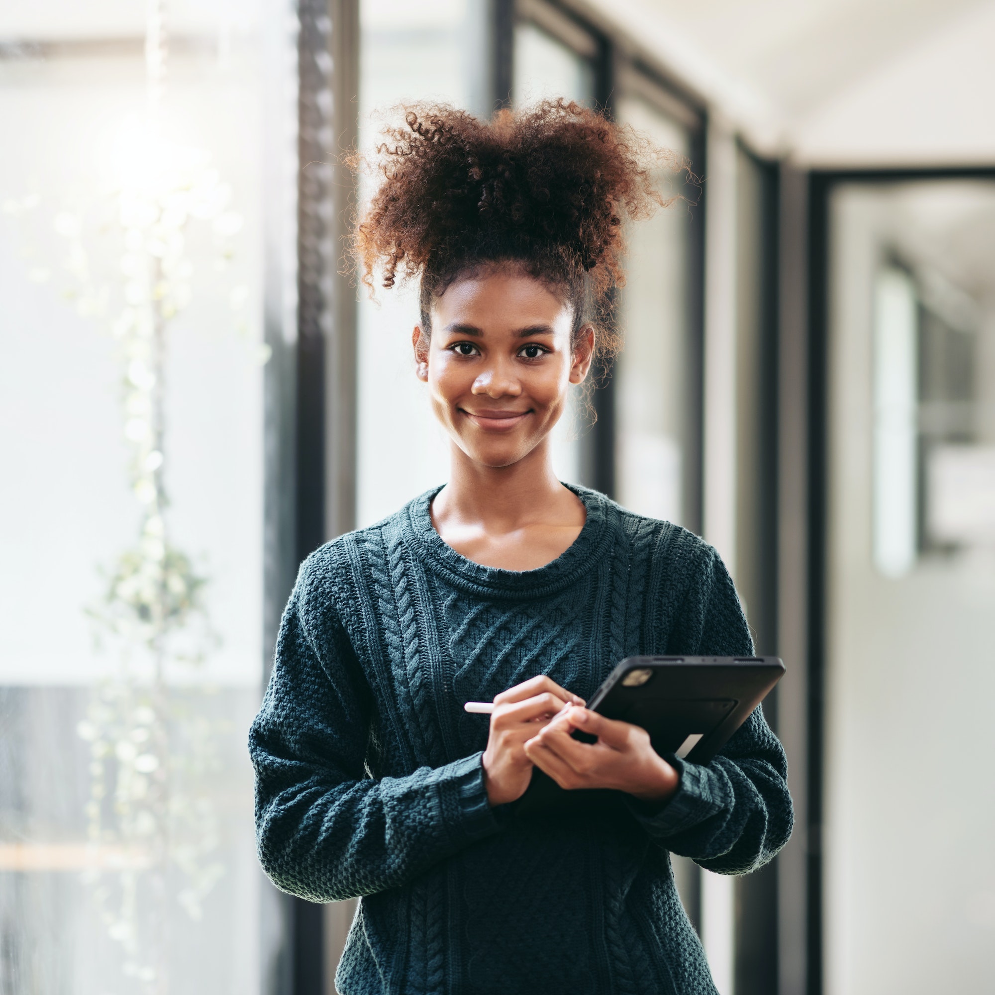 African american woman in sweater writing information and homework on digital tablet after studying